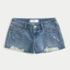 Lågmidjade minishorts i mediumtvättad denim med slitna detaljer Lågmidjade minishorts i mediumtvättad denim med slitna detaljer