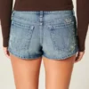 Ultra låg midja, medium tvätt, minishorts i denim med blommig brodyr Ultra låg midja, medium tvätt, minishorts i denim med blommig brodyr