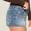 Ultra låg midja, medium tvätt, minishorts i denim med blommig brodyr Ultra låg midja, medium tvätt, minishorts i denim med blommig brodyr