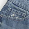 Ultra låg midja, medium tvätt, minishorts i denim med blommig brodyr Ultra låg midja, medium tvätt, minishorts i denim med blommig brodyr